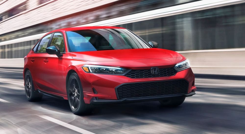 Red 2026 Honda Civic driving down a city street.