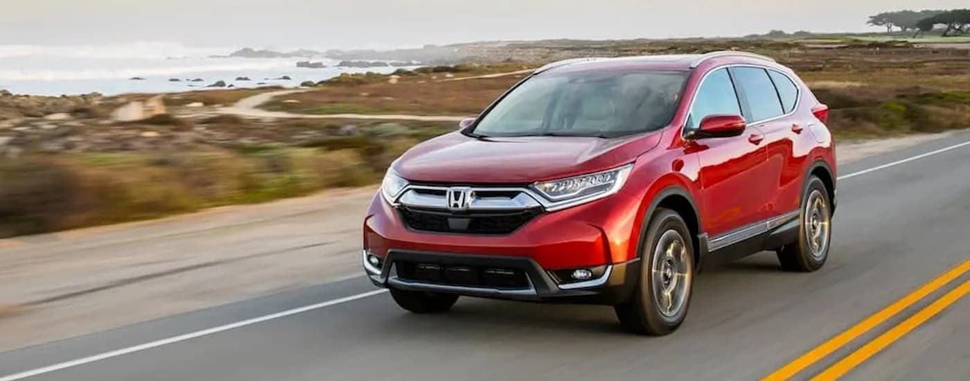 Red 2018 Honda CR-V driving down a road.