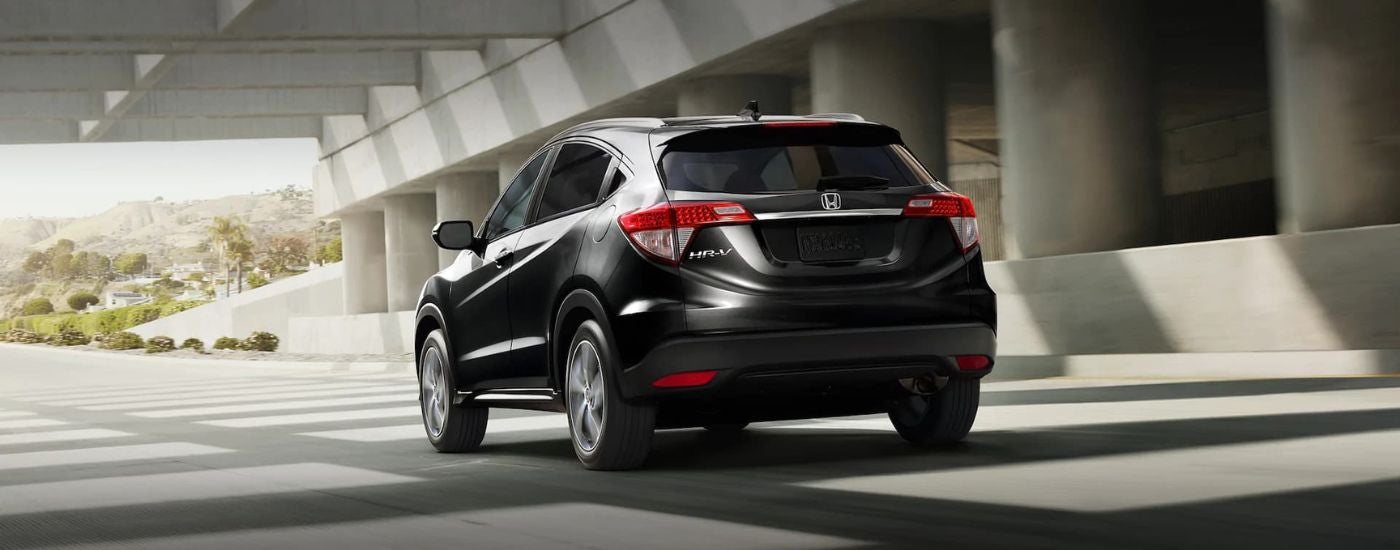 Rear of a black 2021 Honda HR-V driving beneath a bridge.