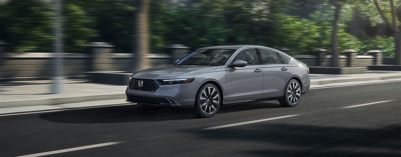 Grey 2026 Honda Accord Touring Hybrid driving down a city street.