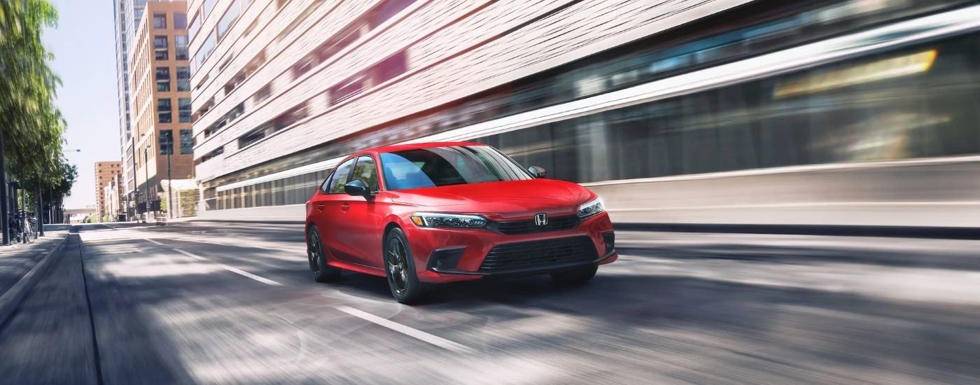 Red 2023 Honda Civic Sport driving through a city