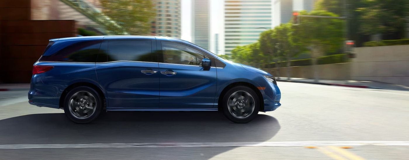 Blue 2024 Honda Odyssey driving through a city