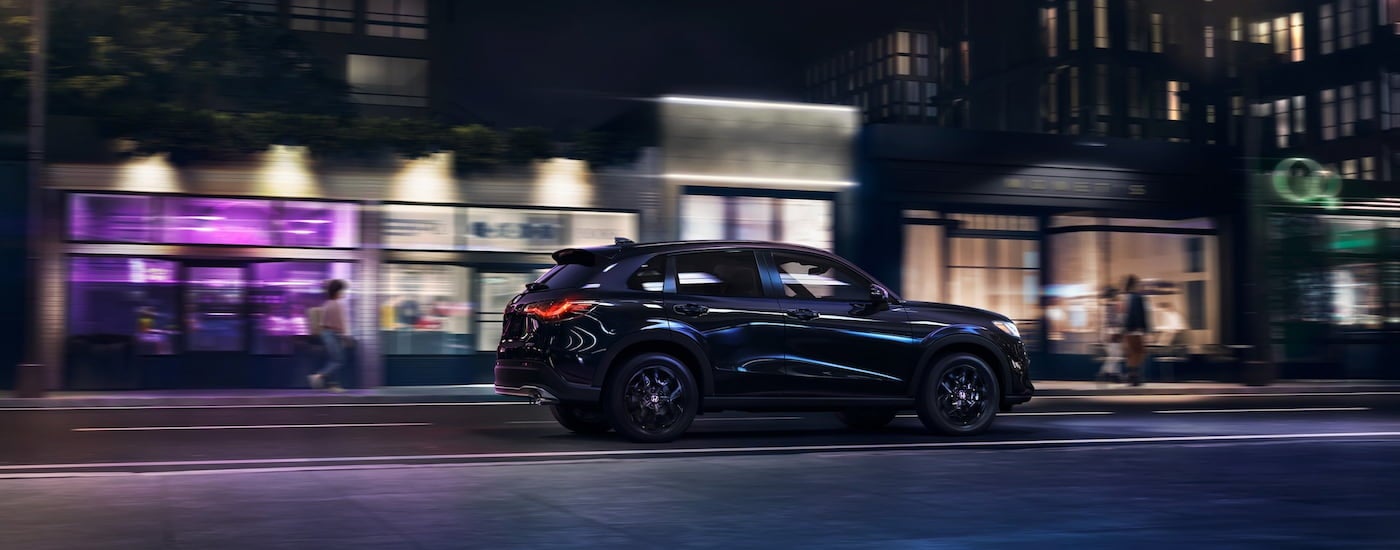 Side of a black 2026 Honda HR-V Sport driving in a city.