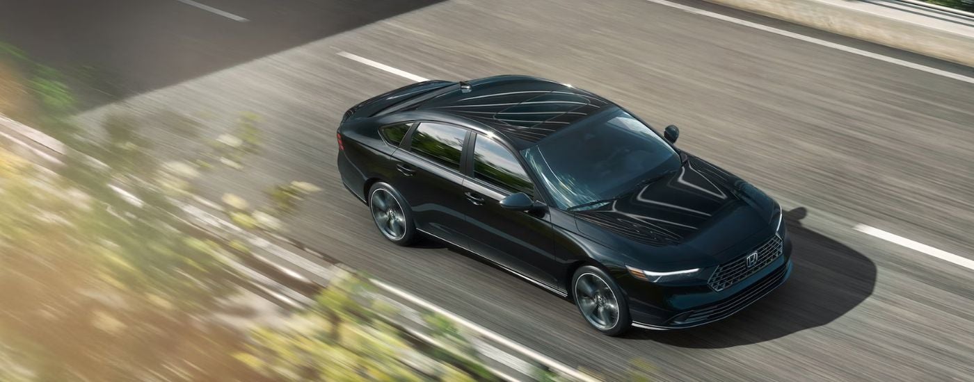 Black 2026 Honda Accord aerial view driving on a road.
