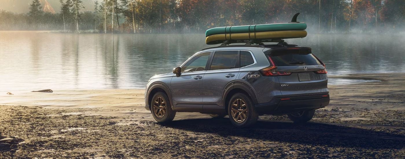Grey 2026 Honda CR-V with paddleboards parked near a lake.