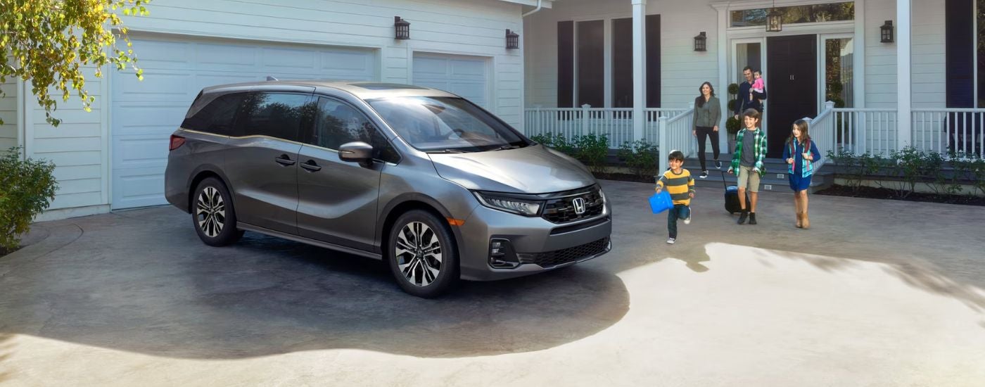 Grey 2026 Honda Odyssey parked in a driveway with a family.