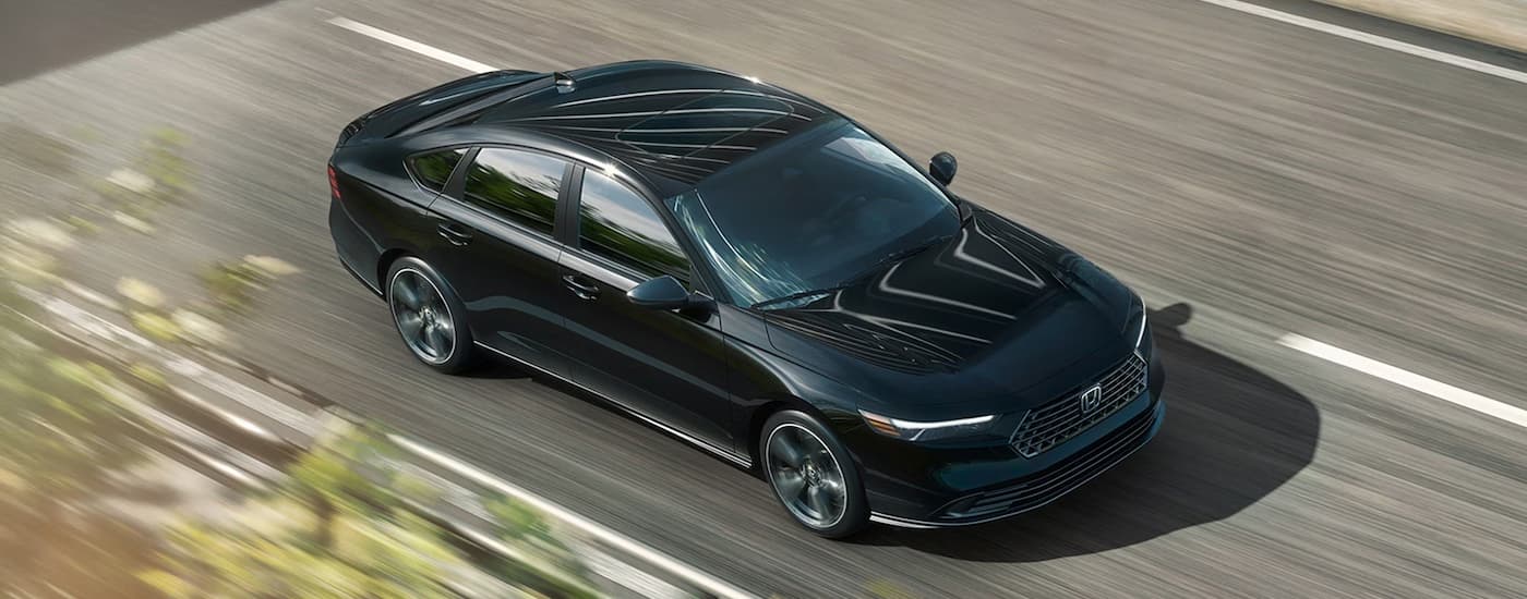 High view of a black 2026 Honda Accord Hybrid driving down a street.