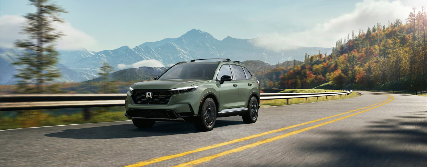 Green 2026 Honda CR-V Hybrid driving to a Honda dealer near Opp