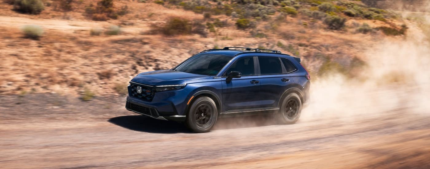 Blue 2026 Honda CR-V TrailSport Hybrid driving off-road.