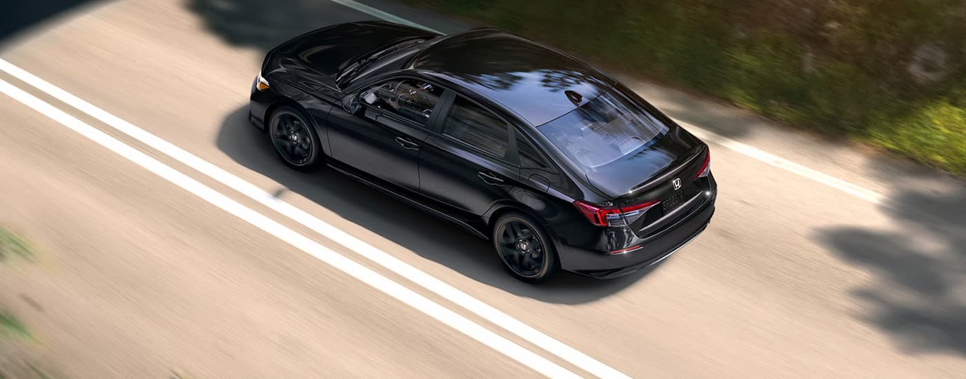 Black 2026 Honda Civic driving down a road.