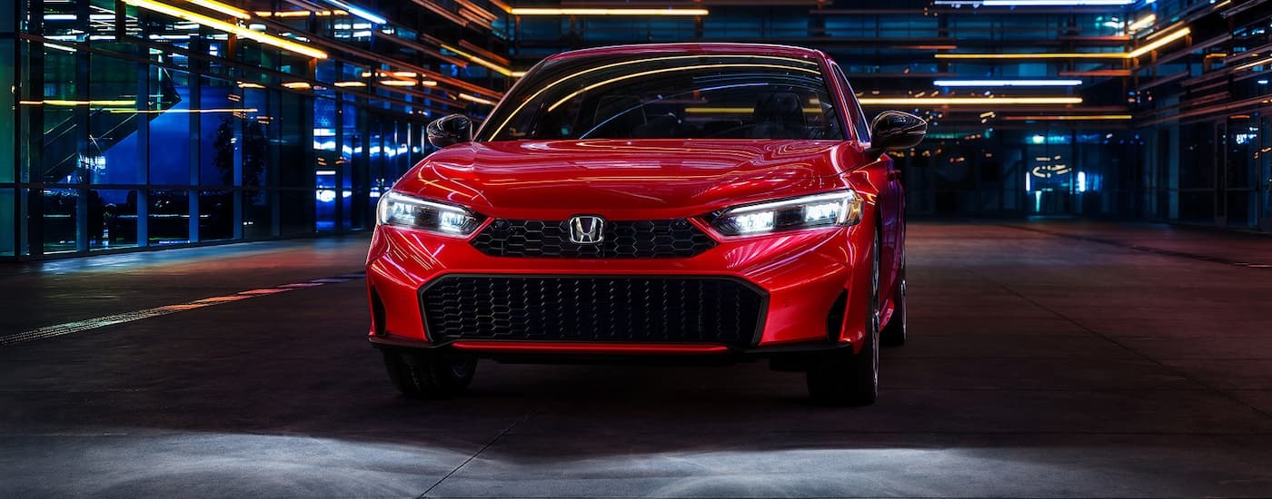 Red 2026 Honda Civic driving down an open road.