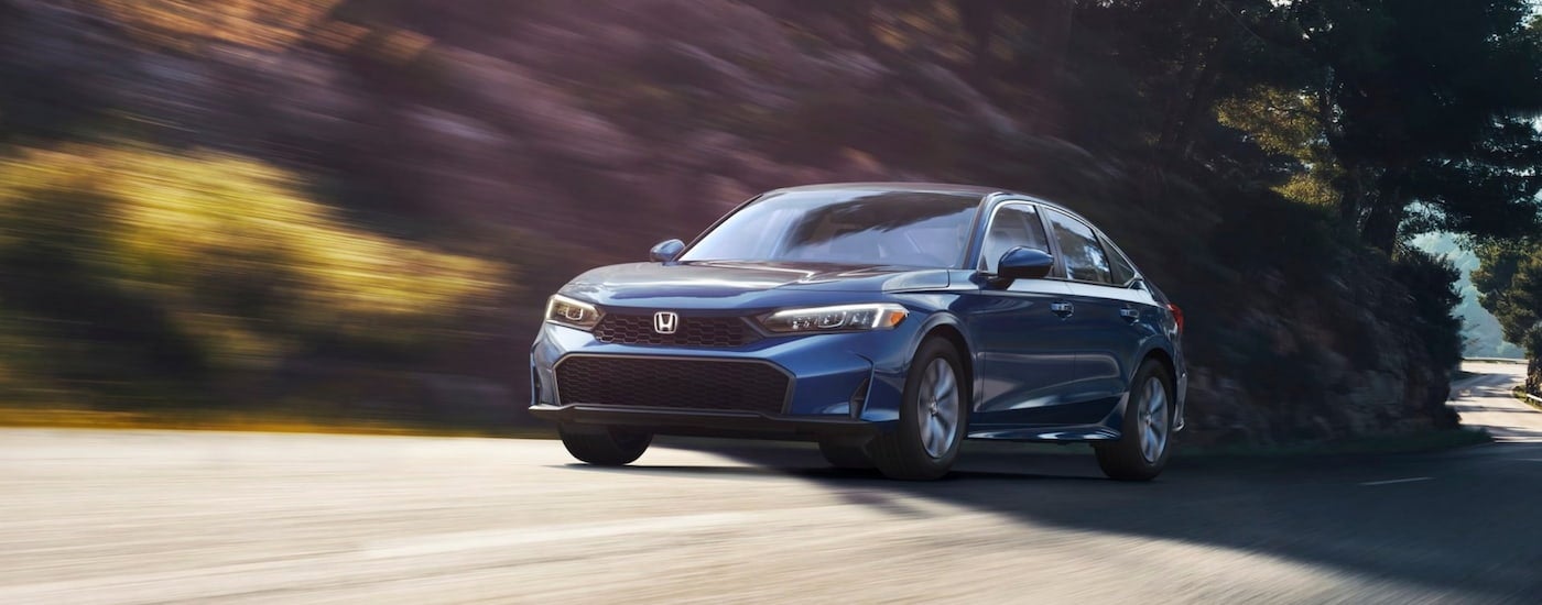 Blue 2026 Honda Civic LX driving down an open road.