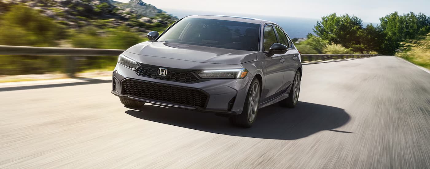 Silver 2026 Honda Civic Sedan driving down an open road.