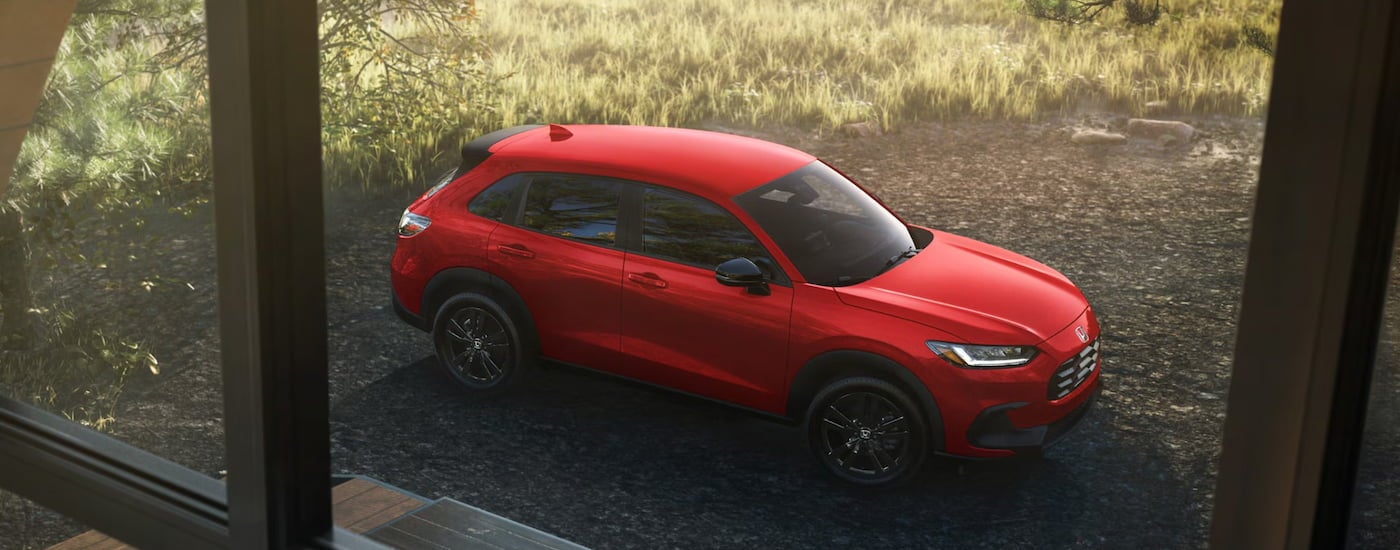 Red 2026 Honda HR-V parked off-road in front of a building.