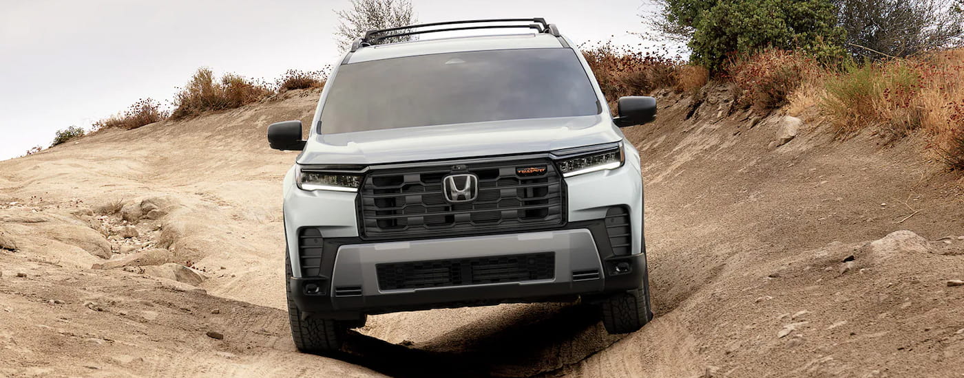 Front of a white 2026 Honda Pilot driving down a hill.