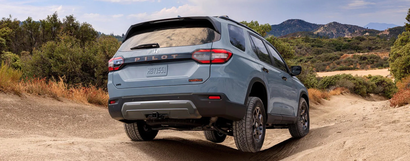 Blue 2026 Honda Pilot Trailsport driving over rocks
