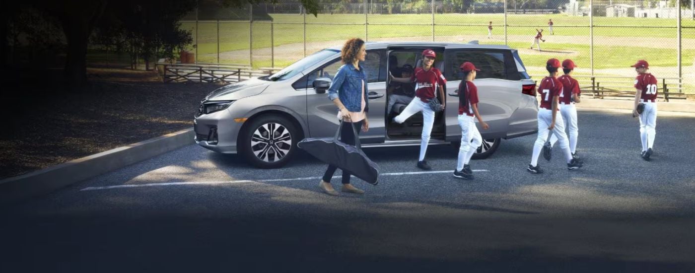 Silver 2026 Honda Odysssey with a little league team exiting.