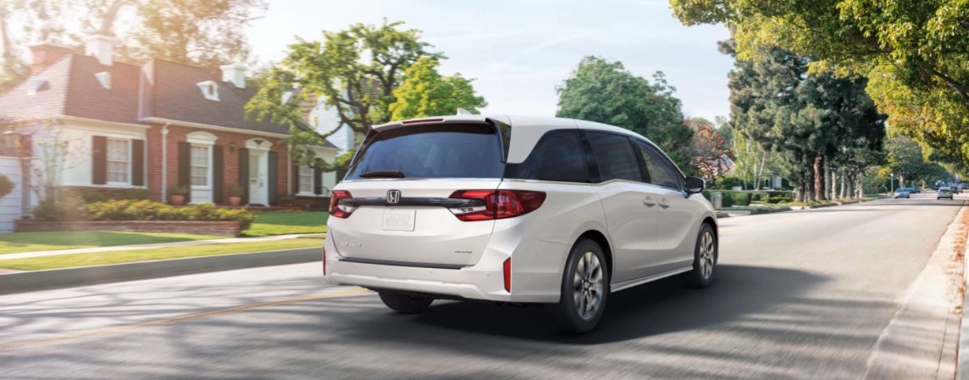 White 2026 Honda Odyssey driving down a residential street.