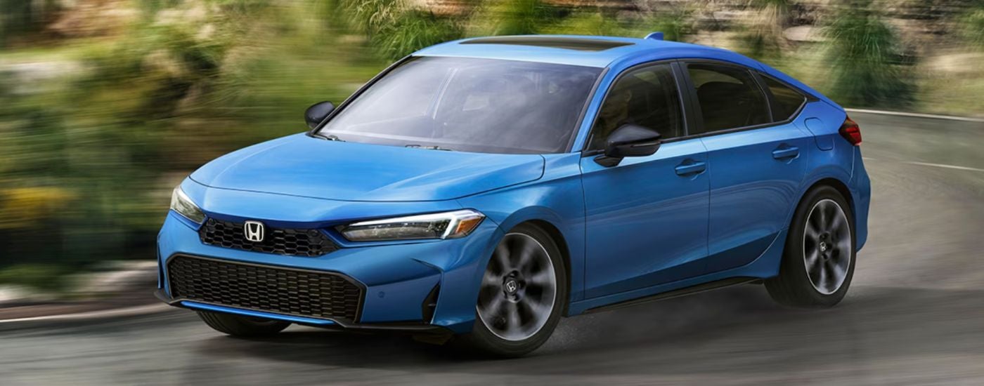 Blue 2026 Honda Civic Hatchback turning a corner on the road.