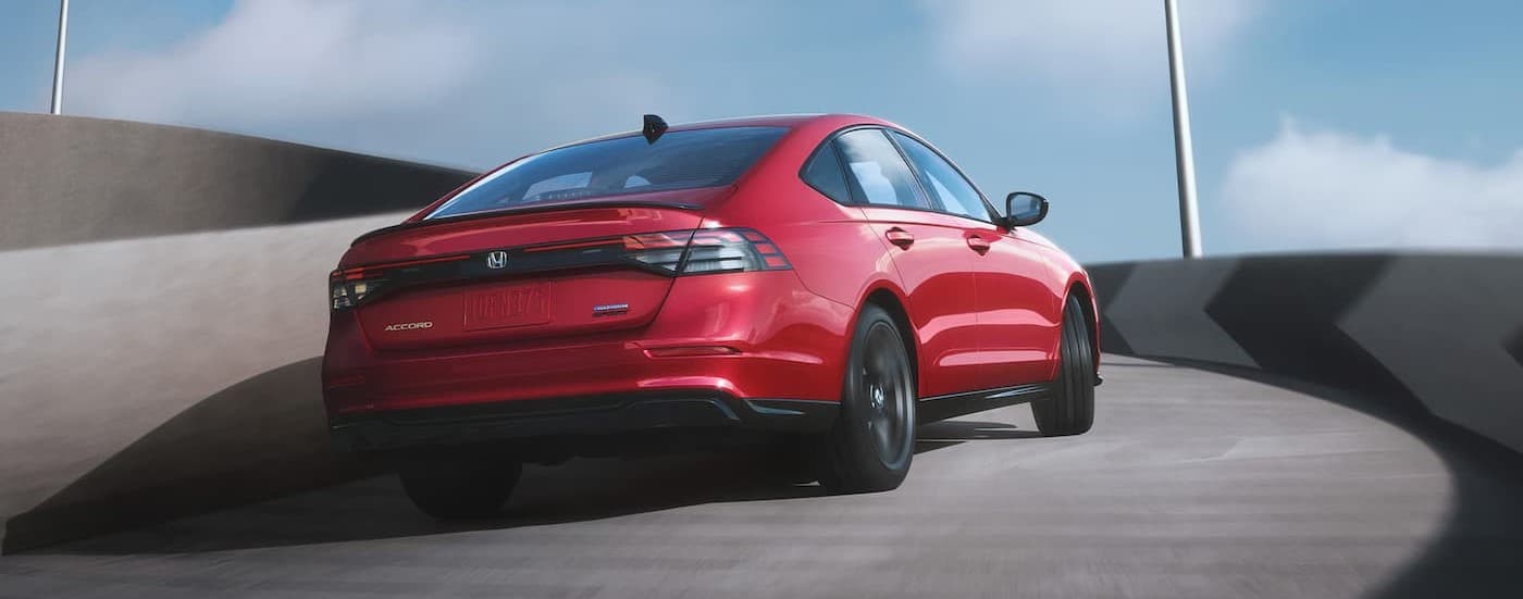 A red 2025 Honda Accord Hybrid driving up a ramp.
