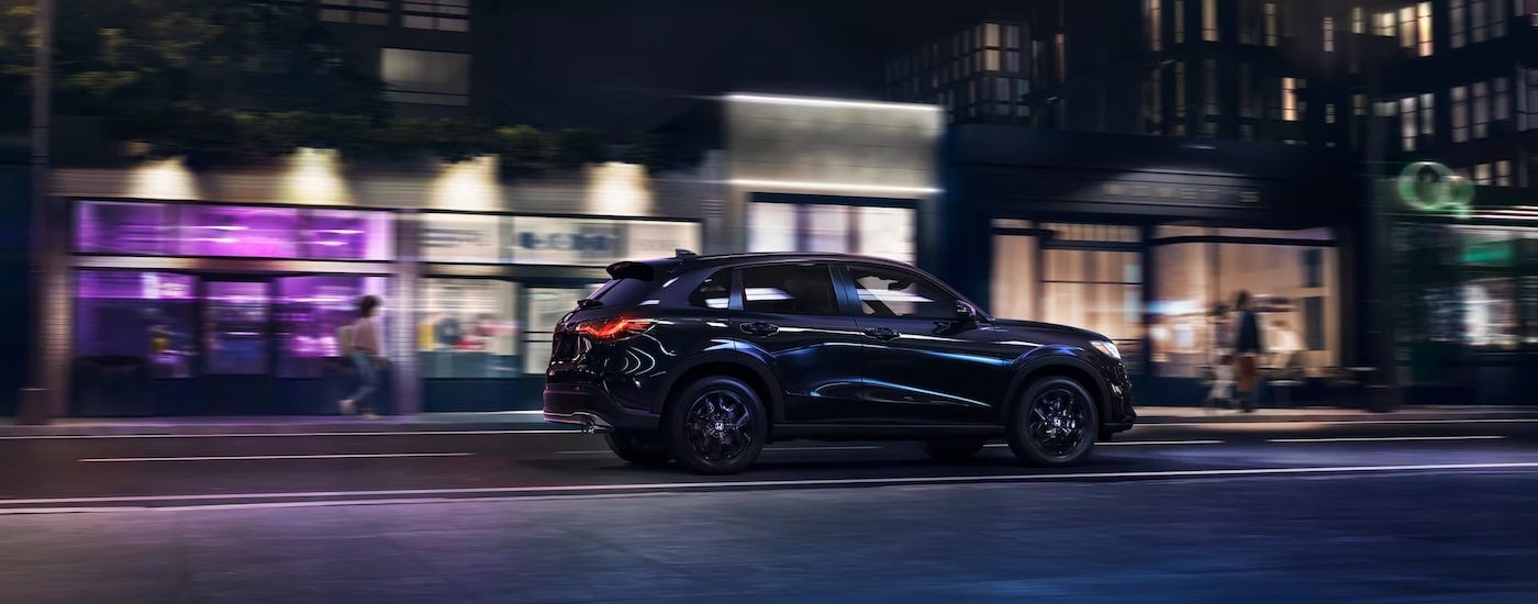 Black 2023 Honda HR-V driving on a city street at night